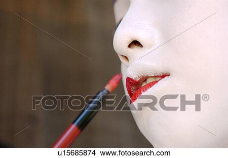 Picture - A Geisha woman applying makeup. Fotosearch