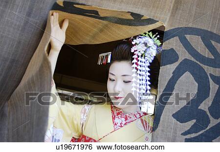 Stock Photograph - A geisha woman coming out from a shop. Fotosearch