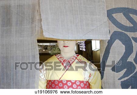 Stock Photograph - A geisha woman standing behind a shop curtain. Fotosearch