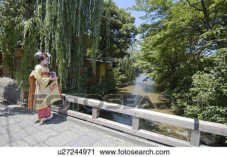 Stock Image - A Geisha woman standing by a river. Fotosearch