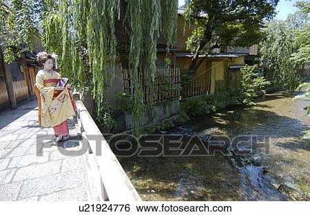 Stock Photograph - A Geisha woman standing by a river. Fotosearch