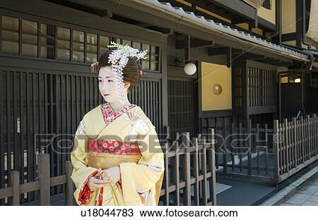 Stock Image - A Geisha woman walking on a street. Fotosearch