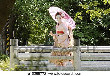 Stock Image - Portrait of a Geisha woman holding umbrella. Fotosearch