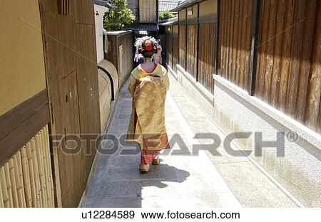 Stock Photo - Rear view of a Geisha woman walking on a street. Fotosearch