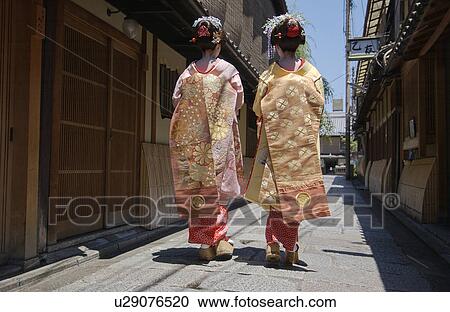 Rear view of two Geisha women walking on a street View Large Photo Image Stock Image - Rear view of two Geisha women walking on a street. Fotosearch