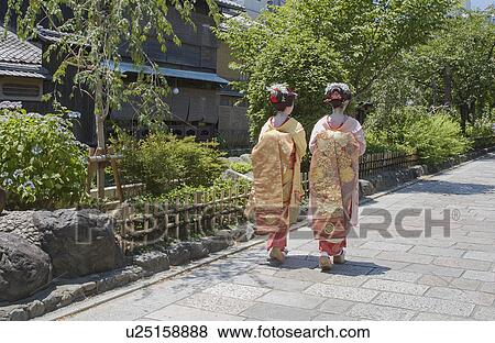 Stock Photo - Rear view of two Geisha women walking on a street. Fotosearch