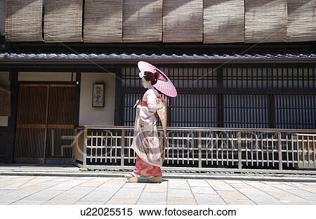Stock Photography - Side view of a Geisha woman walking on a street. Fotosearch