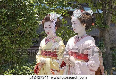 Stock Image - Two Geisha women walking on a street. Fotosearch