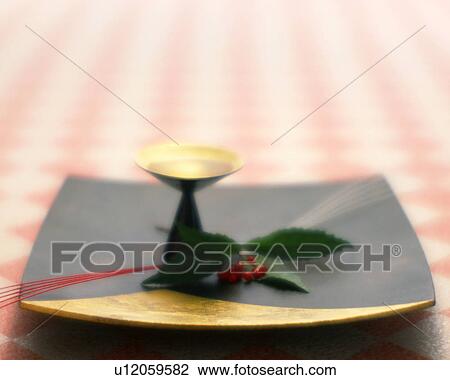 Stock Image - Sake cup and nandina. Fotosearch