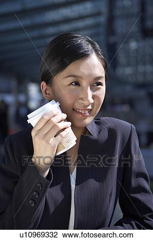 Stock Image - Young Businesswoman Holding Coffee Cup, Looking Away. Fotosearch