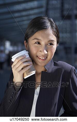 Stock Image - Young Businesswoman Holding Coffee Cup, Looking Away. Fotosearch