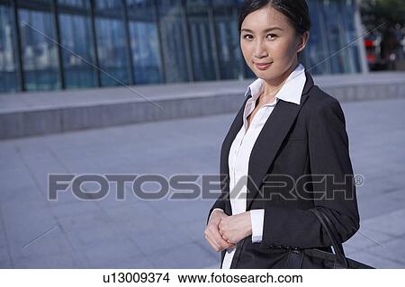 Picture - Young Businesswoman Standing in Street, Carrying Briefcase, Smiling. Fotosearch
