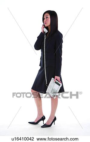 Young woman in business suit, holding telephone, side view View Large Photo Image Stock Image - Young woman in business suit, holding telephone, side view. Fotosearch