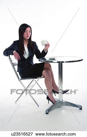 Young woman in business suit, relaxing on chair and holding a cup, full length View Large Photo Image Stock Photo - Young woman in business suit, relaxing on chair and holding a cup, full length. Fotosearch