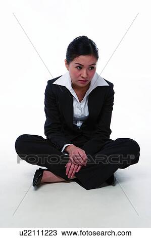 Stock Image - Young woman in business suit, sitting on floor. Fotosearch