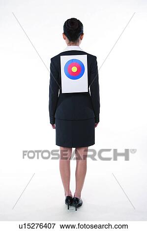 Stock Photo - Young woman in business suit, standing, wearing a target on back, rear view, full length. Fotosearch