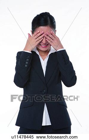 Stock Photography - Young woman in business suit, standing, hands covering eyes. Fotosearch
