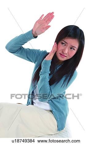 Picture - Young woman looking away, hand raised. Fotosearch