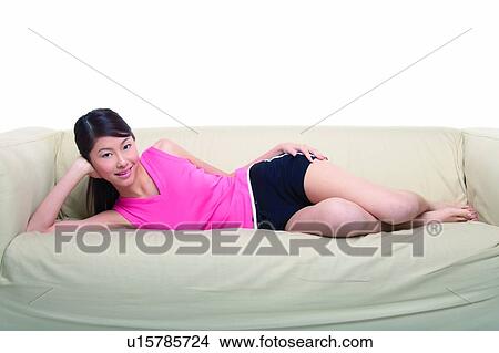 Young woman lying on sofa in side view View Large Photo Image Picture - Young woman lying on sofa in side view. Fotosearch