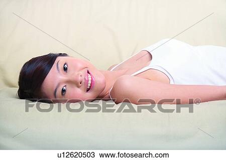 Stock Image - Young woman lying on sofa. Fotosearch