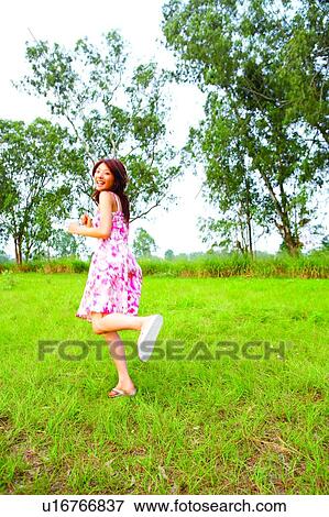Young woman running on grasslands, laughing View Large Photo Image Stock Photo - Young woman running on grasslands, laughing. Fotosearch