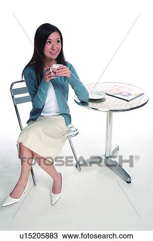 Young woman sitting and holding a cup View Large Photo Image Stock Image - Young woman sitting and holding a cup. Fotosearch