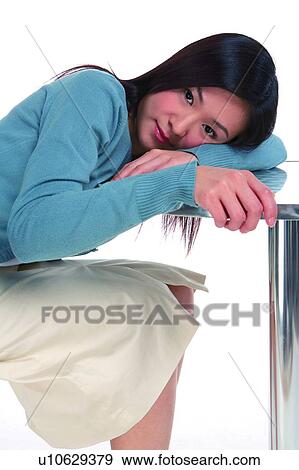 Stock Photo - Young woman sitting and leaning to the table. Fotosearch