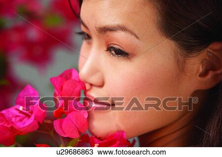 Young woman standing near flower, turning back and smiling, close up View Large Photo Image Stock Image - Young woman standing near flower, turning back and smiling, close up. Fotosearch