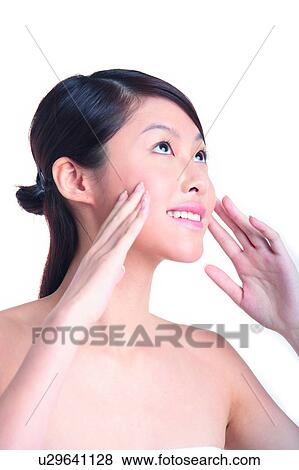 Stock Photo - Young girl standing with hands next to face and is looking forward. Fotosearch