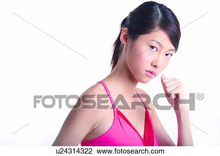 Stock Image - Young woman holding in fist, looking at camera. Fotosearch