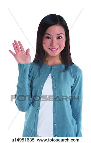 Stock Photography - Young woman standing, hand raised. Fotosearch