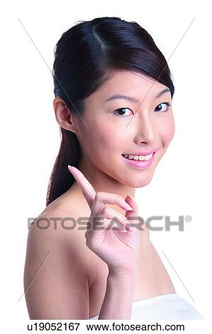 Stock Photo - Young woman standing with finger pointing up. Fotosearch