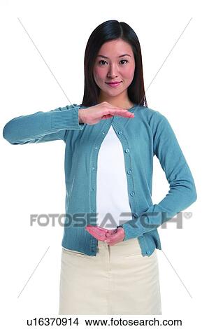 Picture - Young woman standing with one hand up and one hand down. Fotosearch