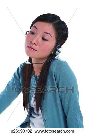 Stock Image - Young woman wearing headphone, looking down and thinking. Fotosearch