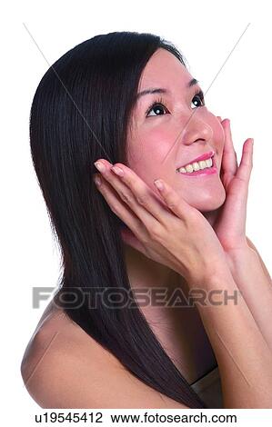 Stock Image - Young woman with long hair, smiling, hands cupped, looking up. Fotosearch