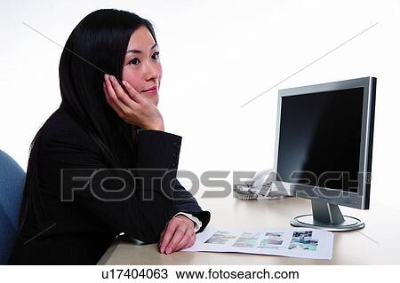 Stock Image - Young woman in business suit, hand on cheek, thinking, side view. Fotosearch