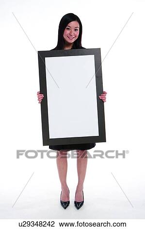 Young woman in business suit, holding cardboard in front View Large Photo Image Stock Image - Young woman in business suit, holding cardboard in front. Fotosearch