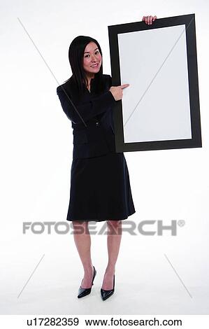 Young woman in business suit, holding cardboard, presenting View Large Photo Image Stock Photo - Young woman in business suit, holding cardboard, presenting. Fotosearch