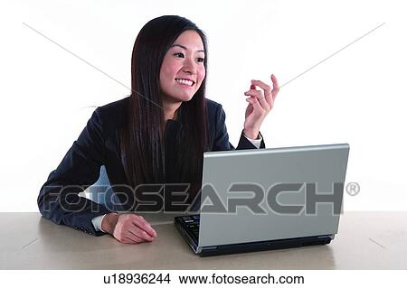 Picture - Young woman in business suit, sitting, looking at notebook happily. Fotosearch