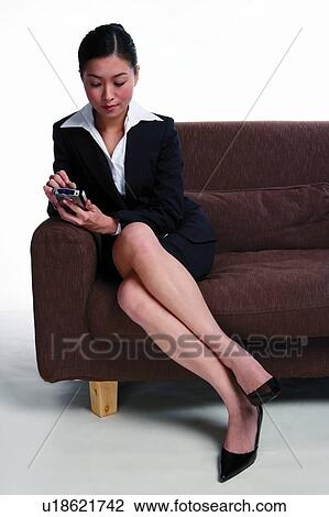 Young woman in business suit, sitting on sofa, using PDA View Large Photo Image Stock Image - Young woman in business suit, sitting on sofa, using PDA. Fotosearch
