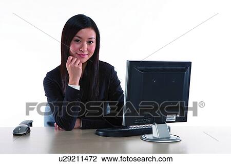 Stock Image - Young woman in business suit, sitting, elbow on table. Fotosearch