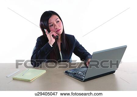 Stock Photo - Young woman in business suit, sitting, talking over the phone. Fotosearch