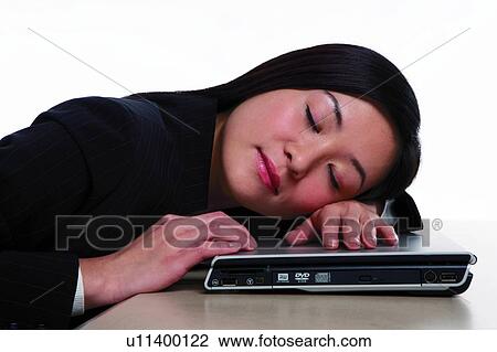 Stock Image - Young woman in business suit, sleeping over the laptop. Fotosearch