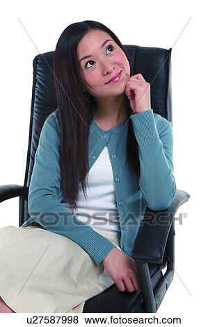 Stock Photo - Young woman relaxing on armchair with hand on cheek. Fotosearch
