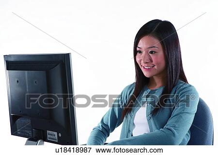 Stock Photo - Young woman sitting and looking at laptop. Fotosearch