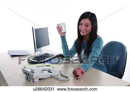 Young woman sitting, holding a cup, office environment View Large Photo Image Stock Image - Young woman sitting, holding a cup, office environment. Fotosearch