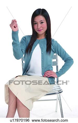 Young woman sitting on chair and raising one hand View Large Photo Image Stock Photograph - Young woman sitting on chair and raising one hand. Fotosearch