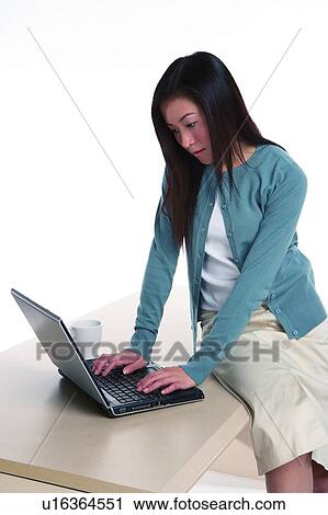 Young woman sitting on table, using computer View Large Photo Image Stock Image - Young woman sitting on table, using computer. Fotosearch