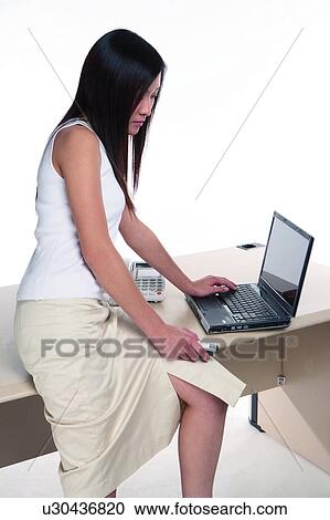 Young woman sitting on table, using computer View Large Photo Image Stock Image - Young woman sitting on table, using computer. Fotosearch