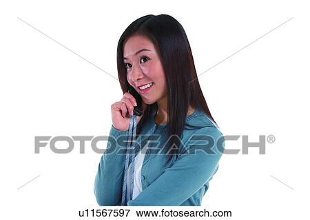 Young woman smiling, holding mobile phone, standing in side view View Large Photo Image Stock Photo - Young woman smiling, holding mobile phone, standing in side view. Fotosearch